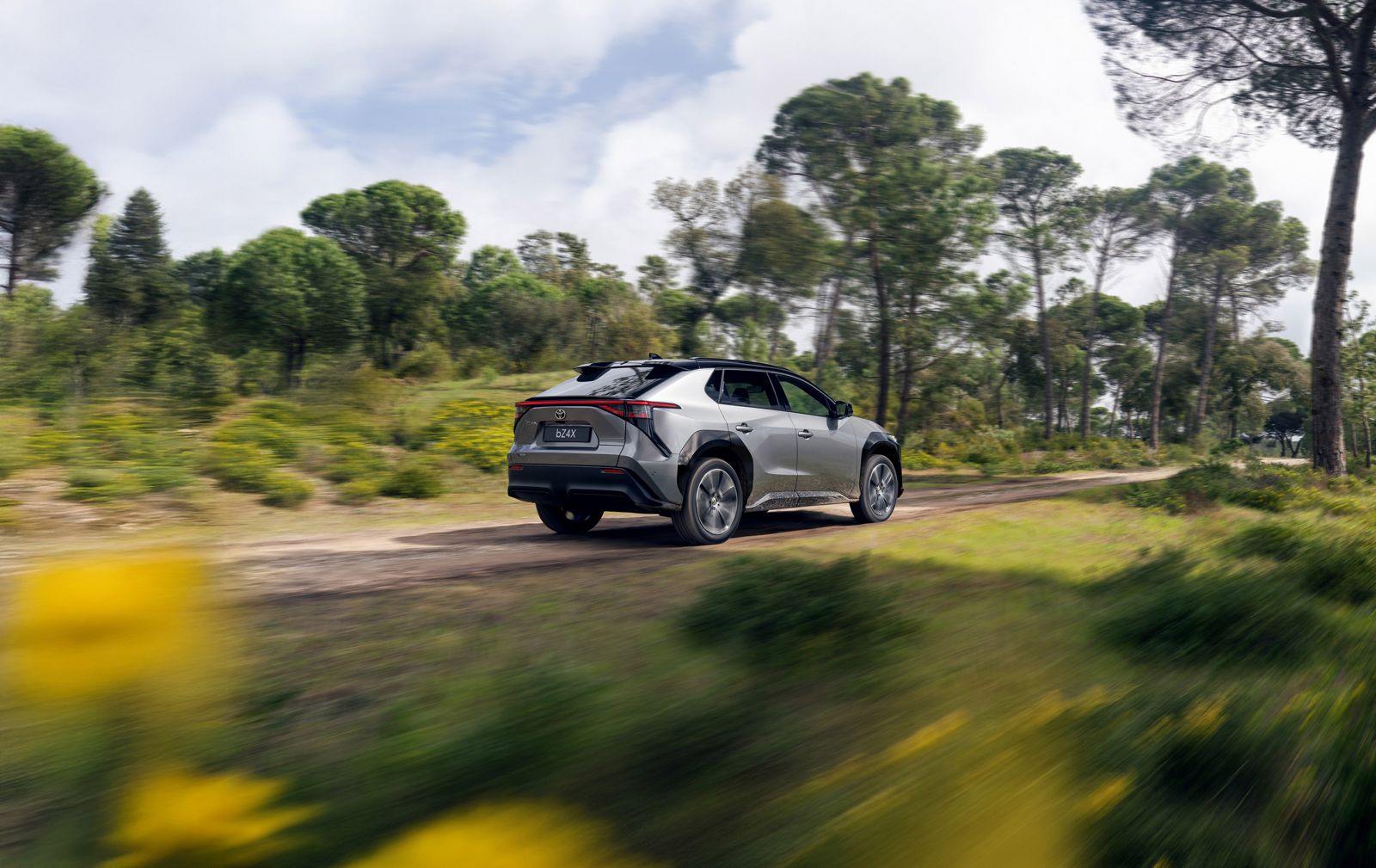 A Toyota bZ drives down a muddy track in the forest 